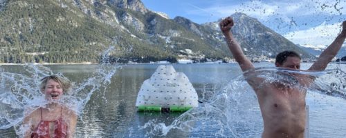 Um für den Sprung in den eiskalten Achensee gewappnet zu sein, gießen die Black Divers Tirol, die das Silvesterschwimmen veranstalten, den Schwimmern einen Kübel Wasser über den Kopf. © Achensee Tourismus